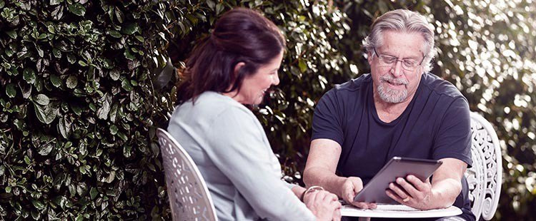 Retired couple on tablet device in garden