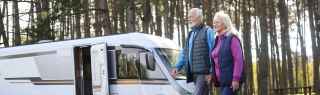 Older couple walking in the forest beside campervan