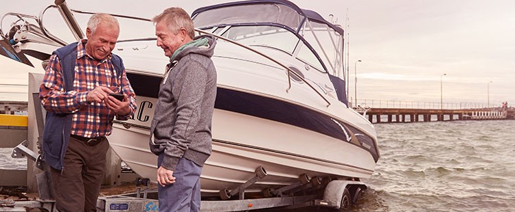 Retired men on smartphone by boat