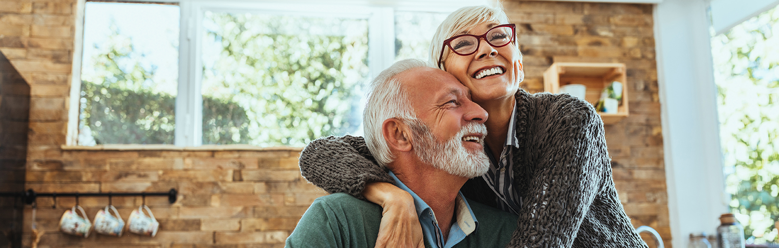 A couple in 60's happy and hugging in kitchen.