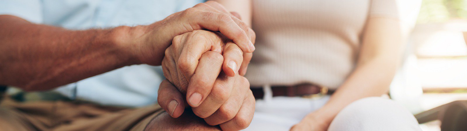 Man and woman with clasped hands resting on knees