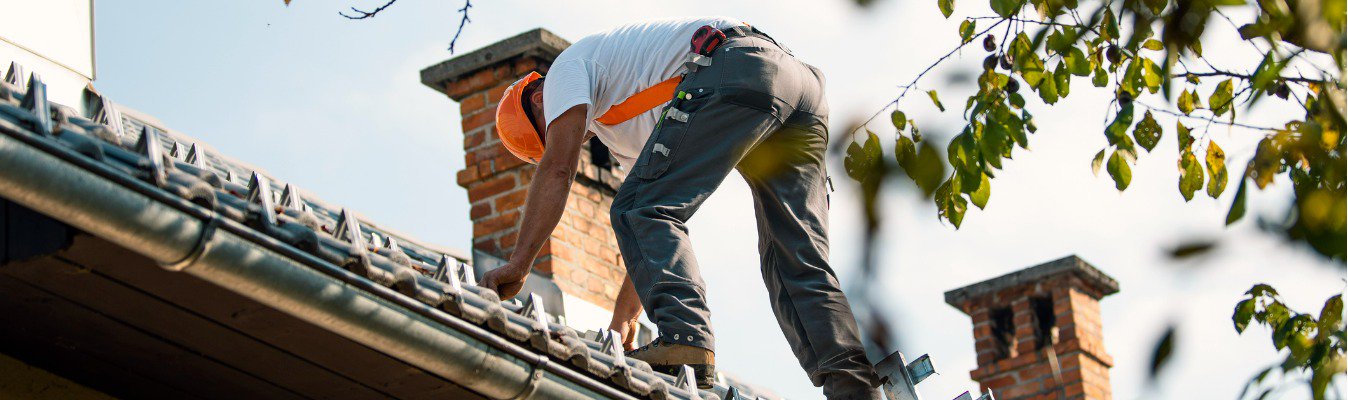 A male tradie working on a tiled roof