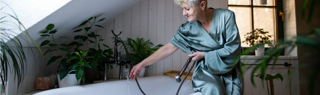 woman sitting on edge of bathtub while it fills