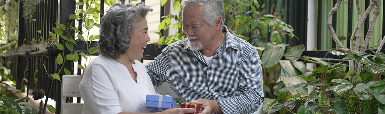 Smiling couple exchanging gifts in a garden