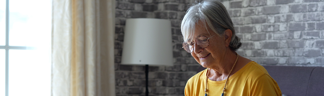 Woman wearing glasses sitting on a couch and enjoying a book