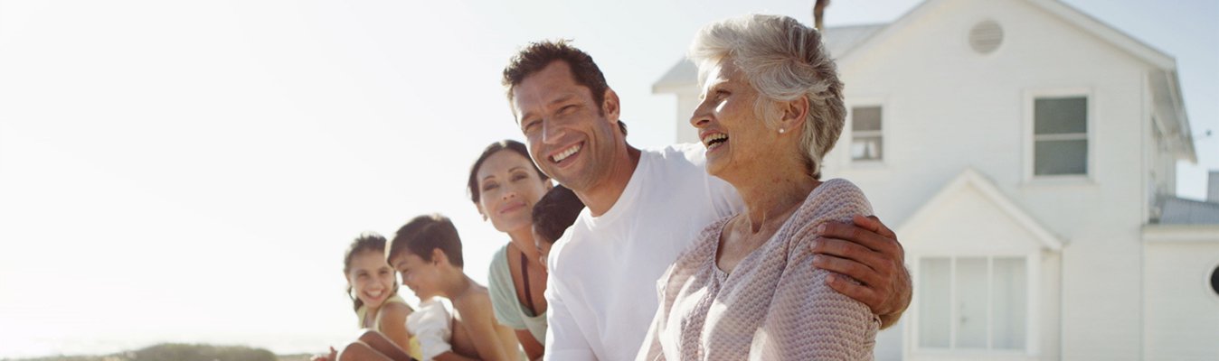 Family smiling together in the sunshine in front of a holiday house