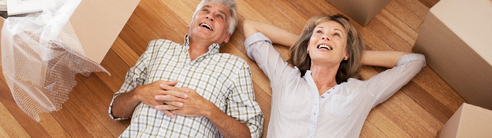 An older couple relaxing on the floor amongst packing boxes