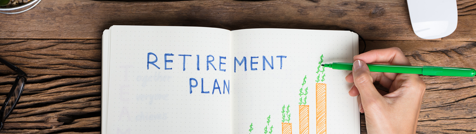 Hands at desk writing out retirement plan