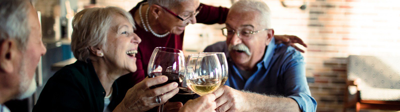group of older people raising wine glasses at restaurant table