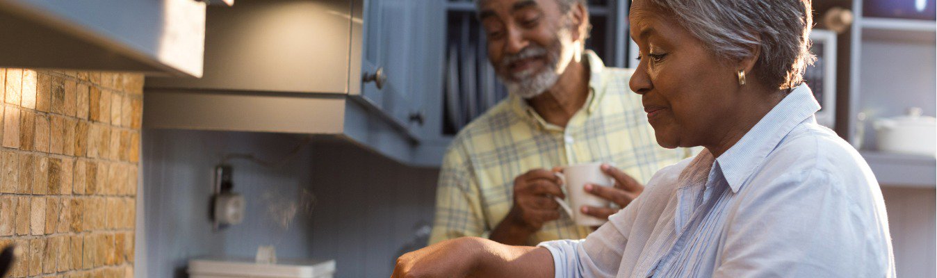 happy senior couple preparing food on stove