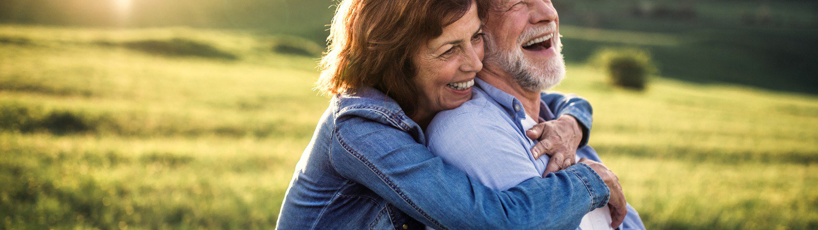 Mature man and woman hugging smiling in field