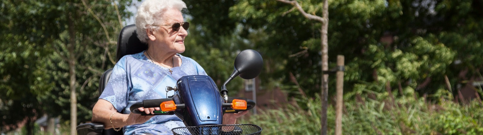 Older woman riding scooter near trees