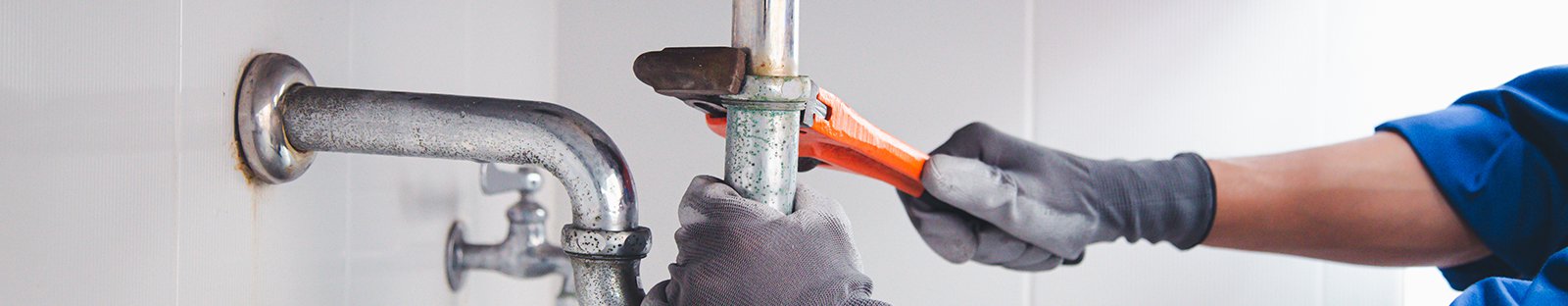 Technician plumber using a wrench to repair a water pipe under the sink. Concept of maintenance, fix water plumbing leaks, replace the kitchen sink drain, cleaning clogged pipes is dirty or rusty.
