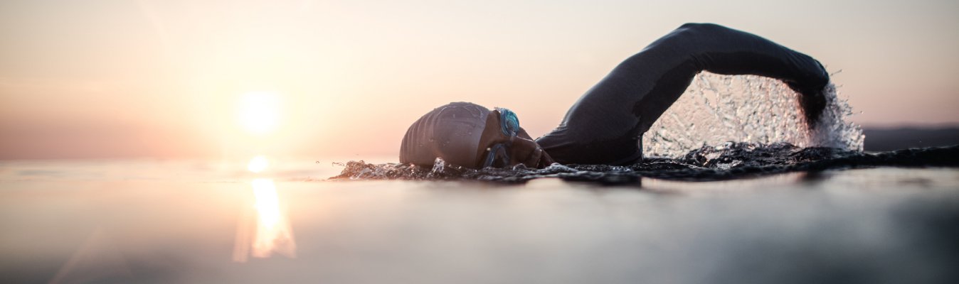 A Retired olympian  is swimming during sunset.