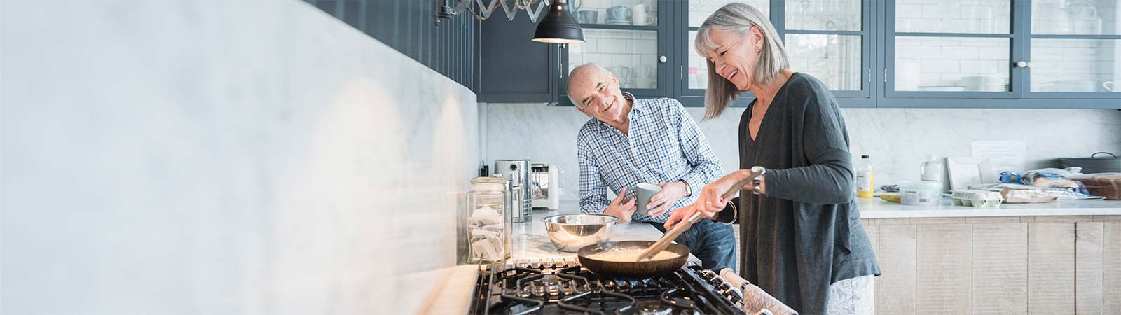 A couple in their 60's cooking & chatting in the kitchen