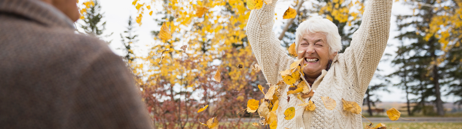 Sennior woman playing with autumn leaves