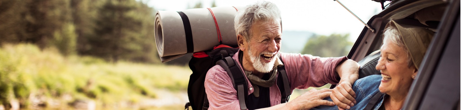 Man wearing a backpack laughing with woman in car