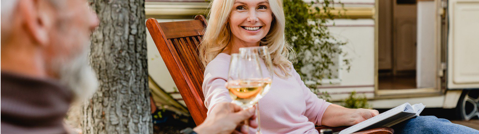 woman in deck chair clinking wine glass with man